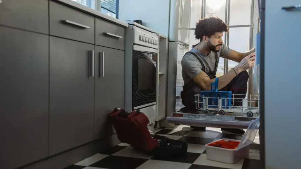 A maintenance worker repairs a kitchen appliance